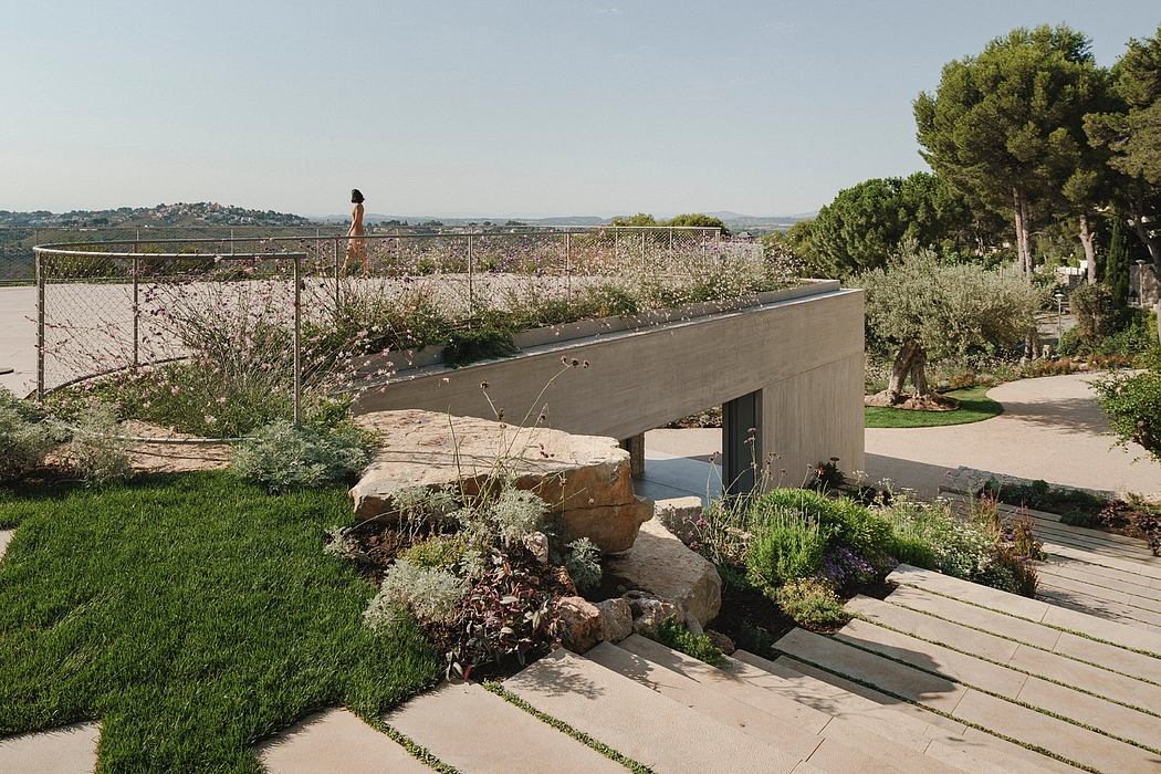 Landscaped garden with a modern concrete footbridge overlooking a scenic vista.