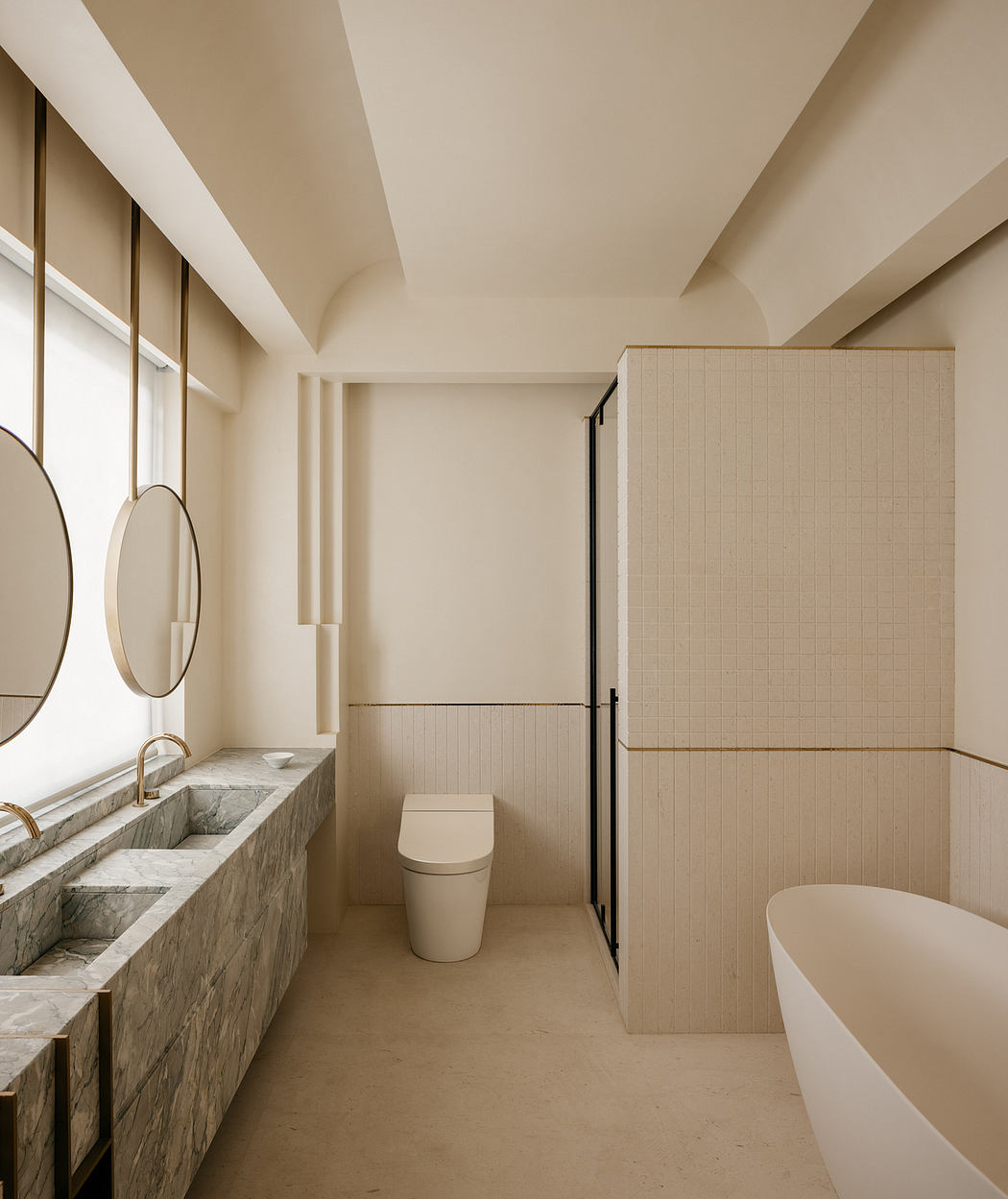 A spacious, minimalist bathroom with stone vanity, freestanding tub, and paneled walls.