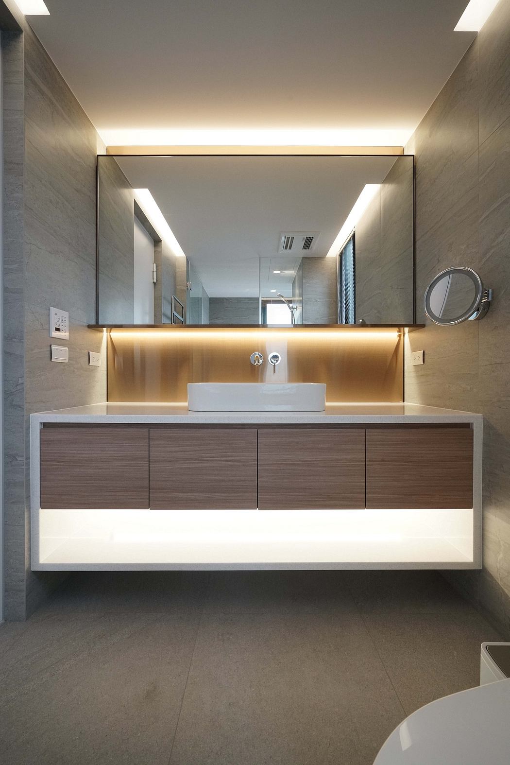 Sleek, modern bathroom with wooden vanity, backlit mirror, and minimalist fixtures.