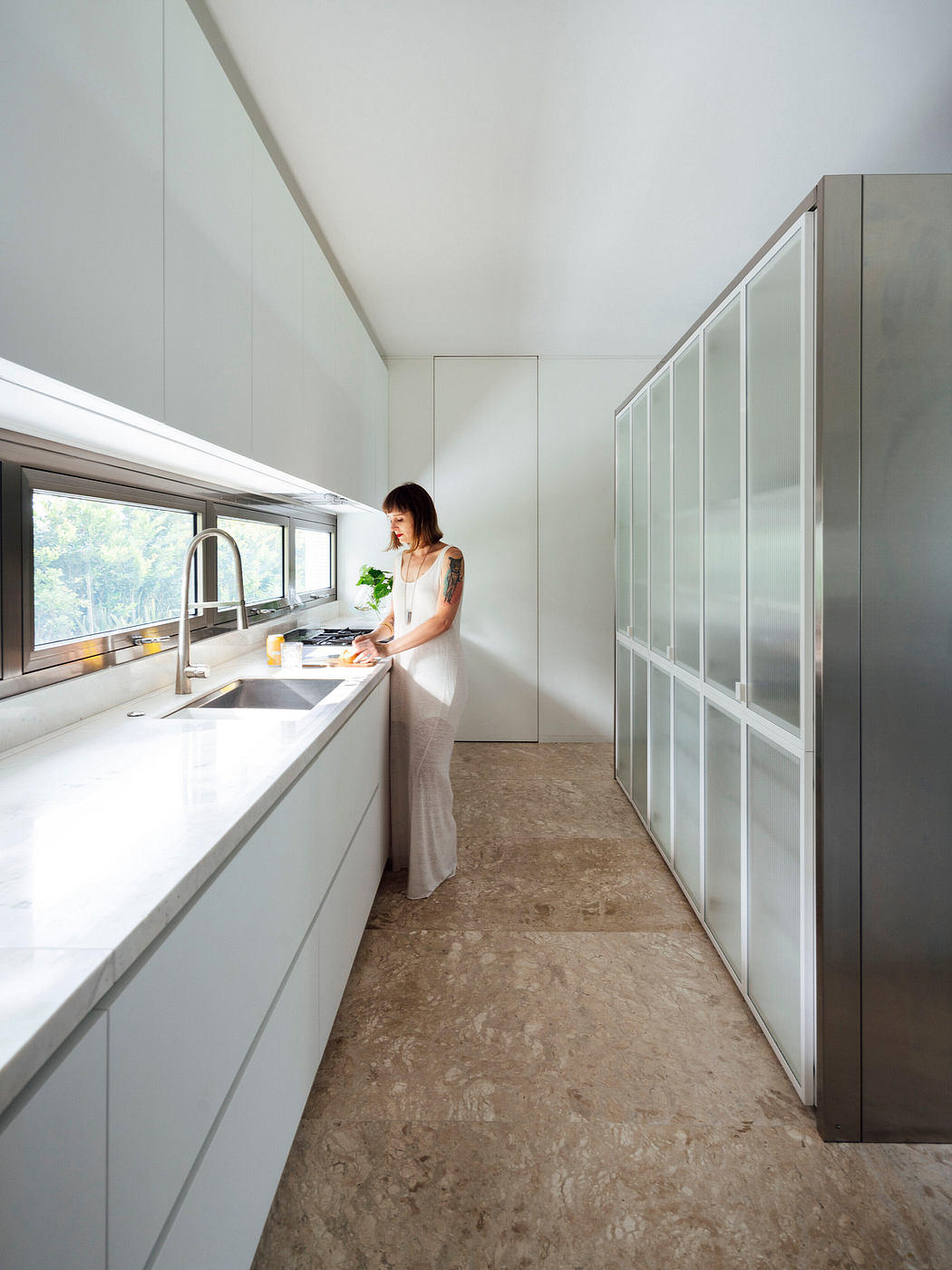 Modern kitchen with sleek white cabinetry, glass-fronted fridge, and cork flooring.