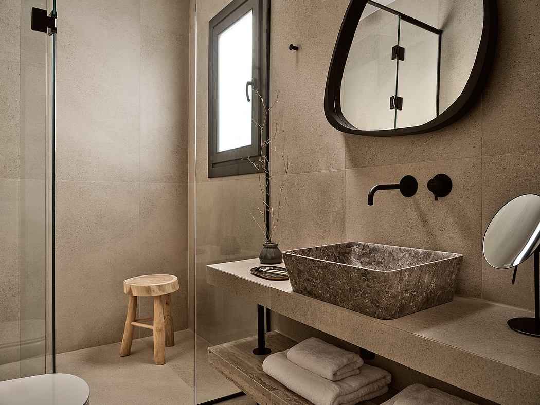 Modern bathroom with stone vessel sink, wood stool, and minimalist mirror frame.