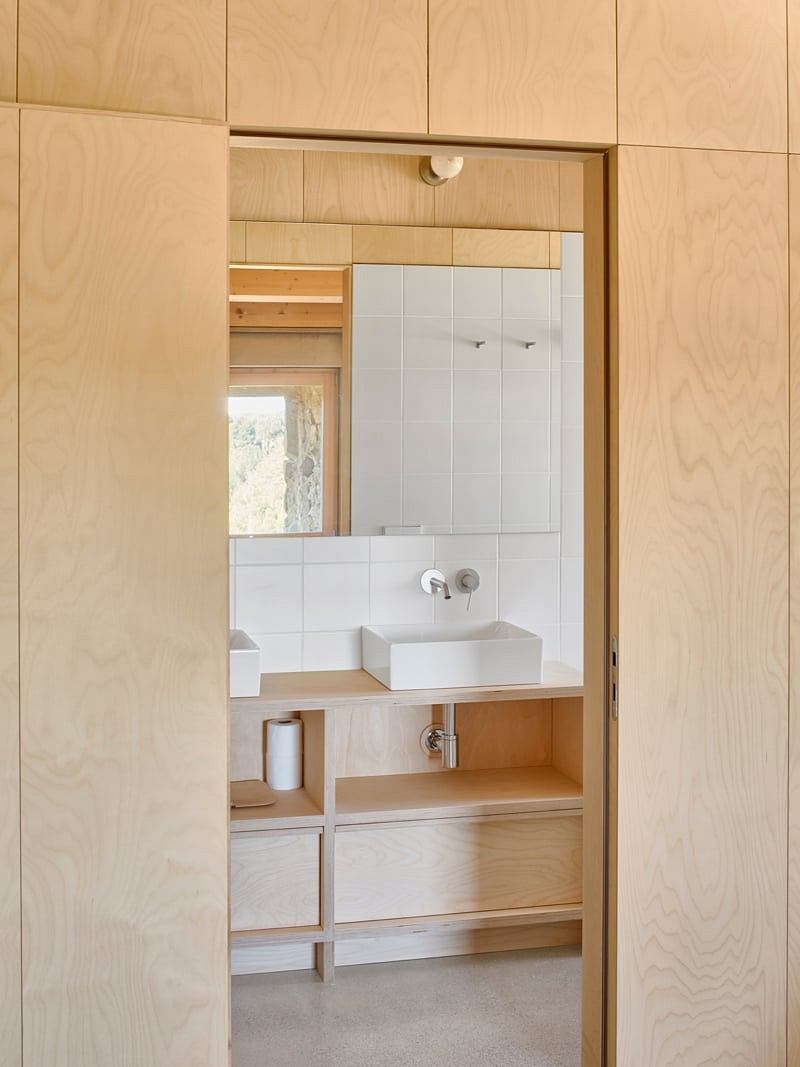 A modern bathroom design featuring wooden panels, a vanity, and a tiled wall.