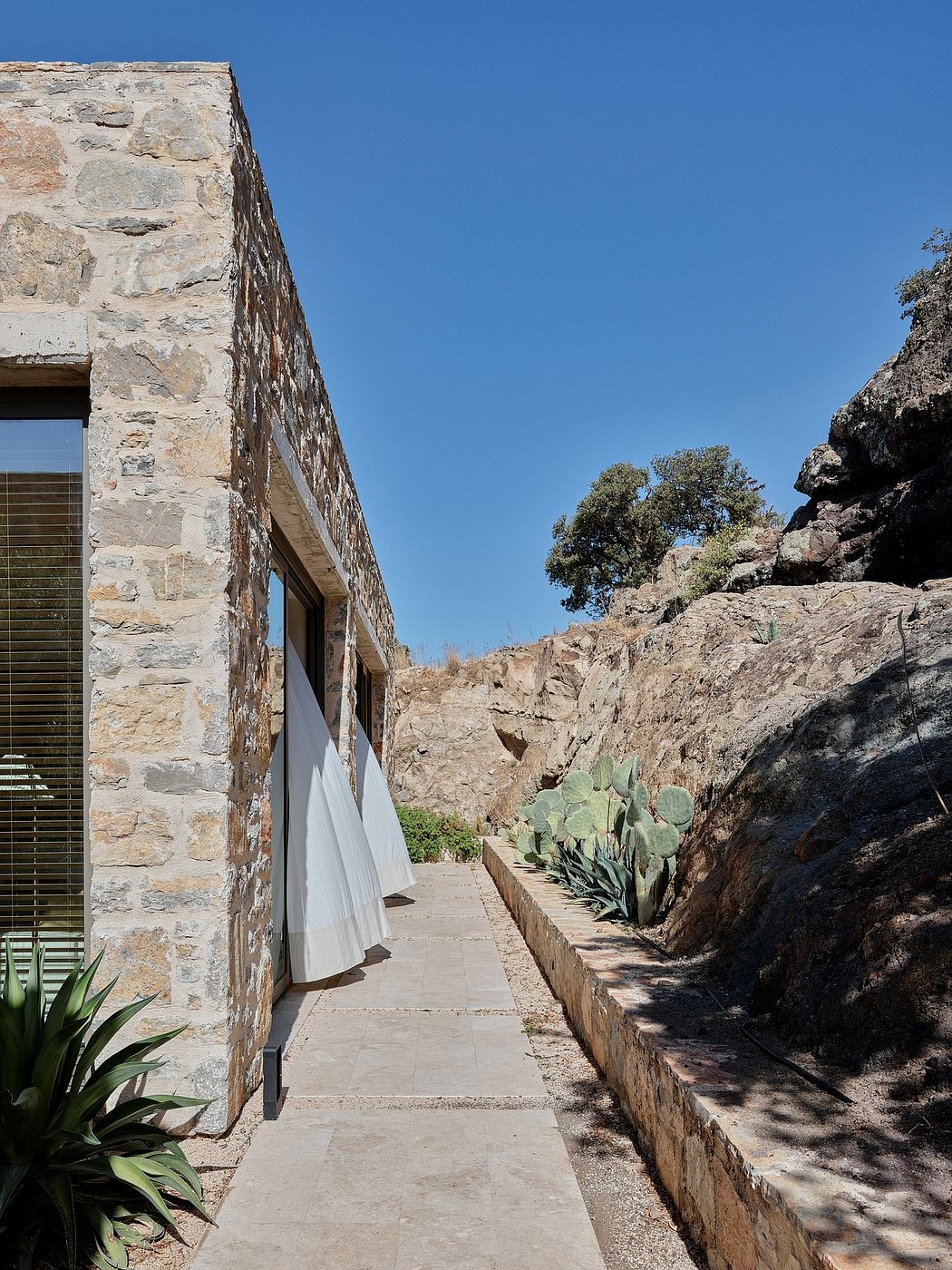 Weathered stone exterior frames a path flanked by cacti, leading to an inviting entrance.