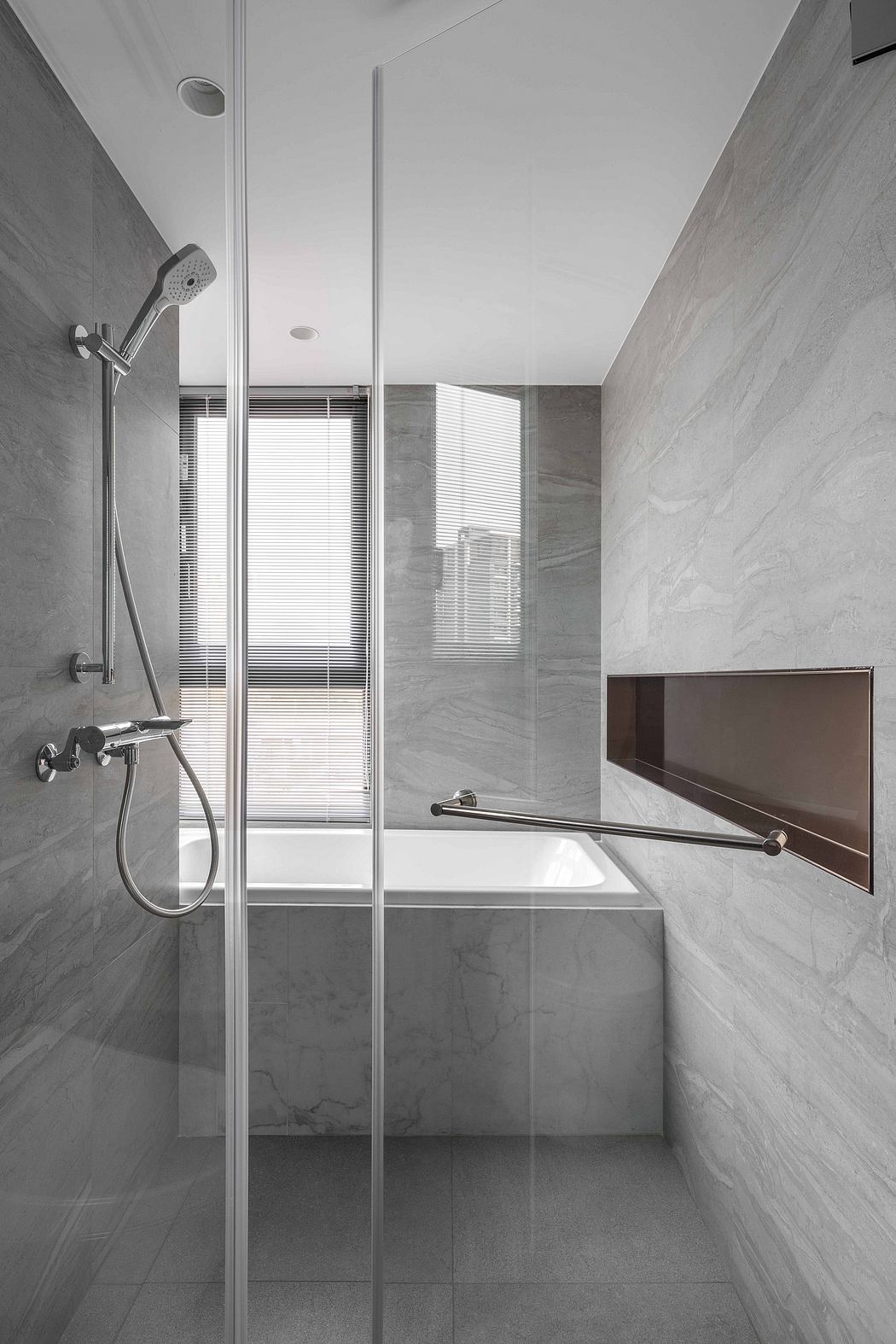 Minimalist bathroom with glass shower enclosure, gray tile walls, and built-in bench.