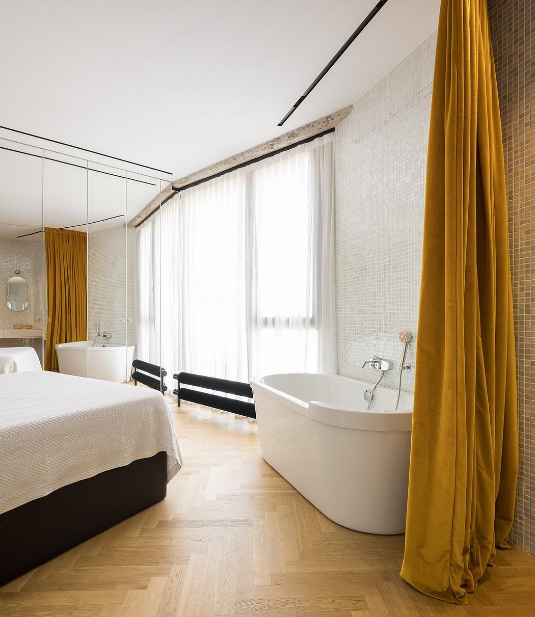 A modern, open-concept bedroom with an ensuite bathtub, white walls, and yellow curtains.