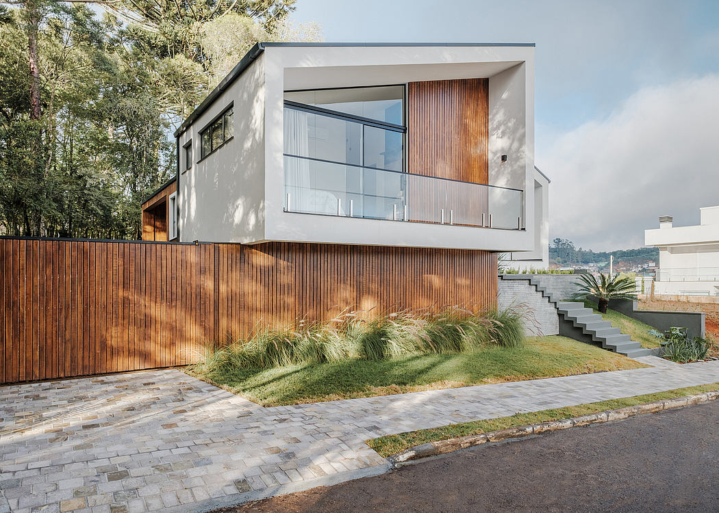 Modern, minimalist home with glass facade, wooden accents, lush landscaping, and stone paving.
