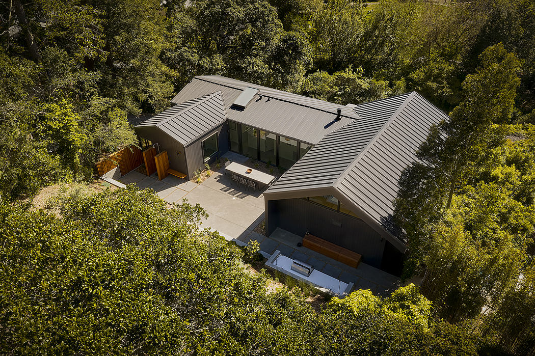 Aerial view of a modern, multi-level home with a unique roofline nestled in lush greenery.