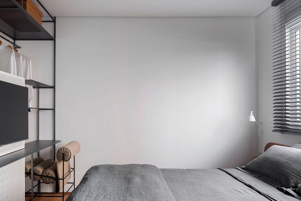 Modern bedroom with minimalist gray and white decor, shelving unit, and window blinds.