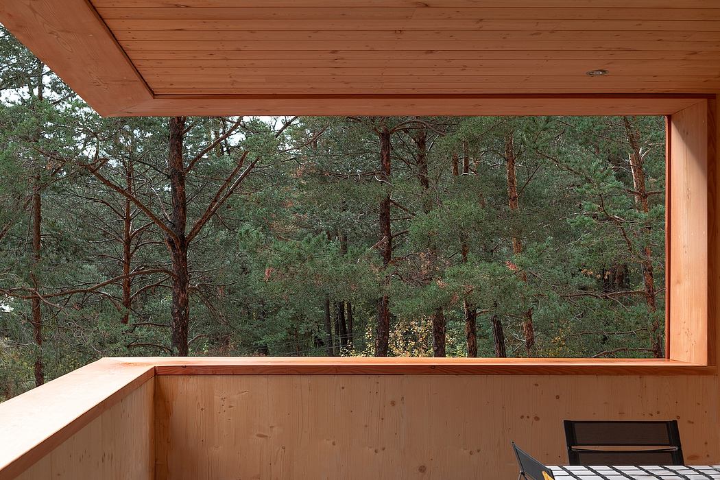 A wooden cabin with a large window overlooking a forested landscape.