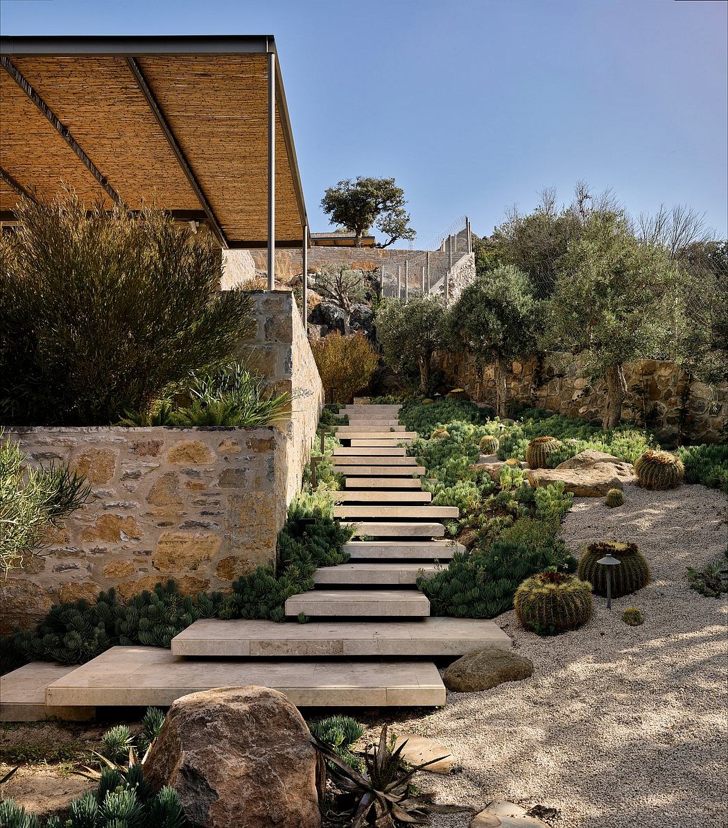 A modern, rustic home nestled in a lush, desert-inspired landscape with stone walls and wooden accents.