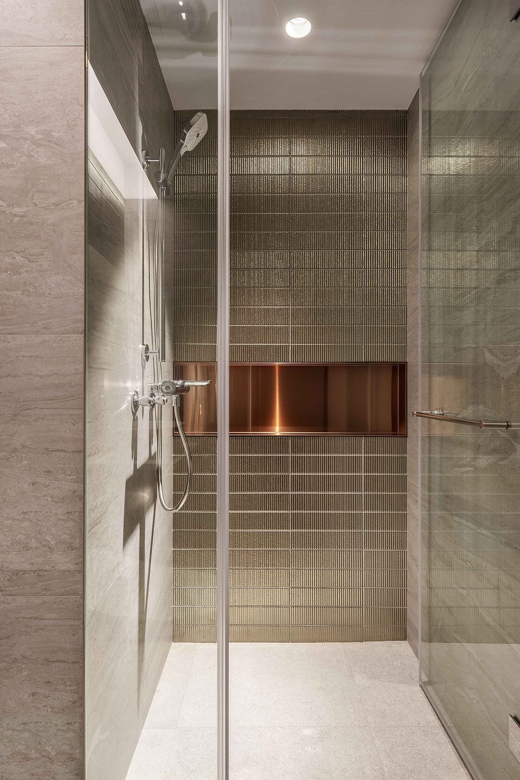 A modern bathroom with sleek gray tiles, copper accents, and a glass shower enclosure.