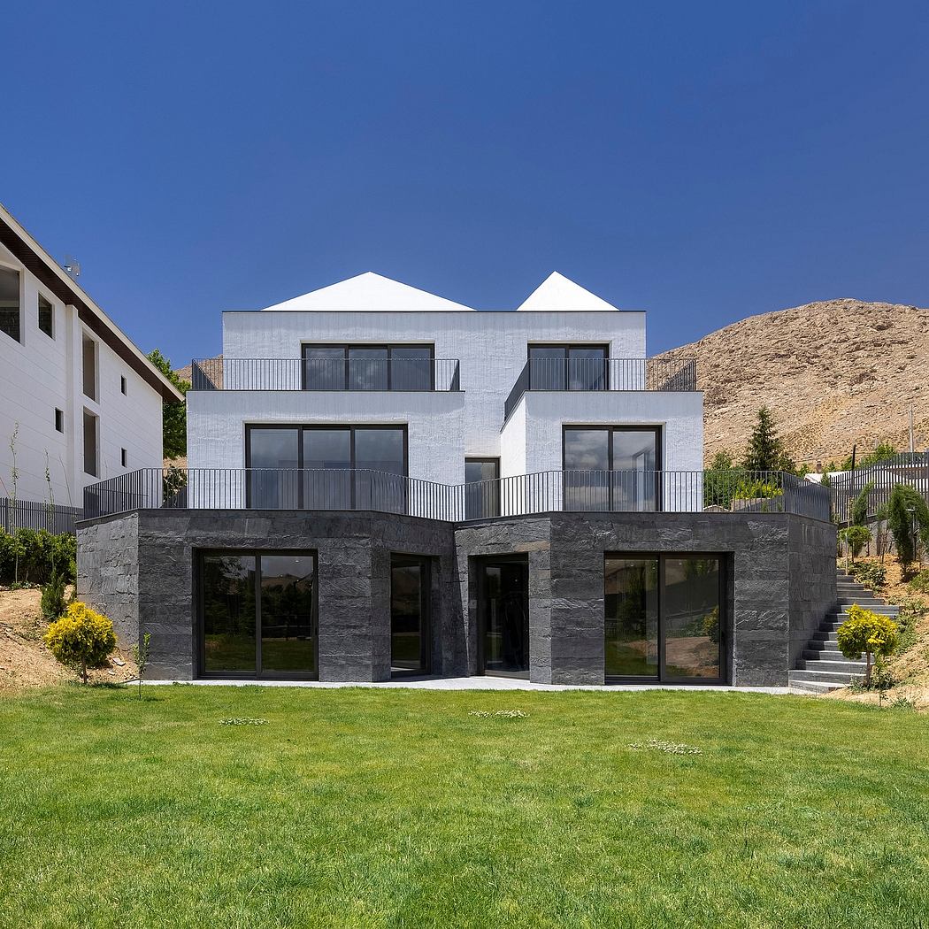 Modern concrete and glass residence with expansive balconies, set against a hilly backdrop.