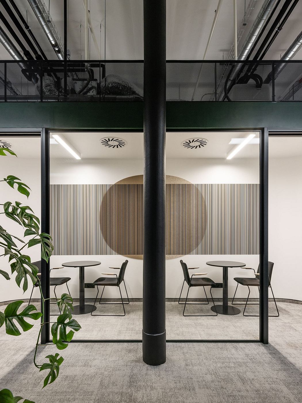 Sleek industrial office interior with minimalist furnishings, greenery accents, and glass partitions.