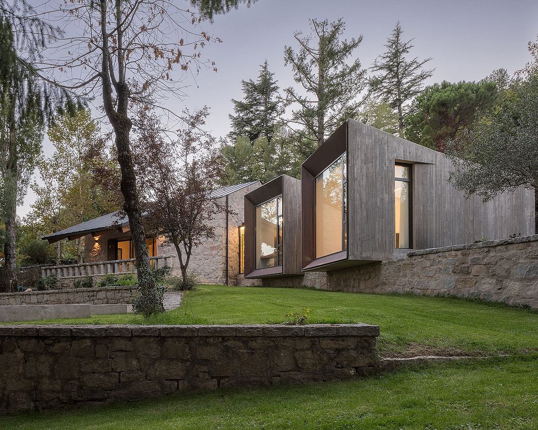 A modern, angular home with large windows set against a forested landscape.