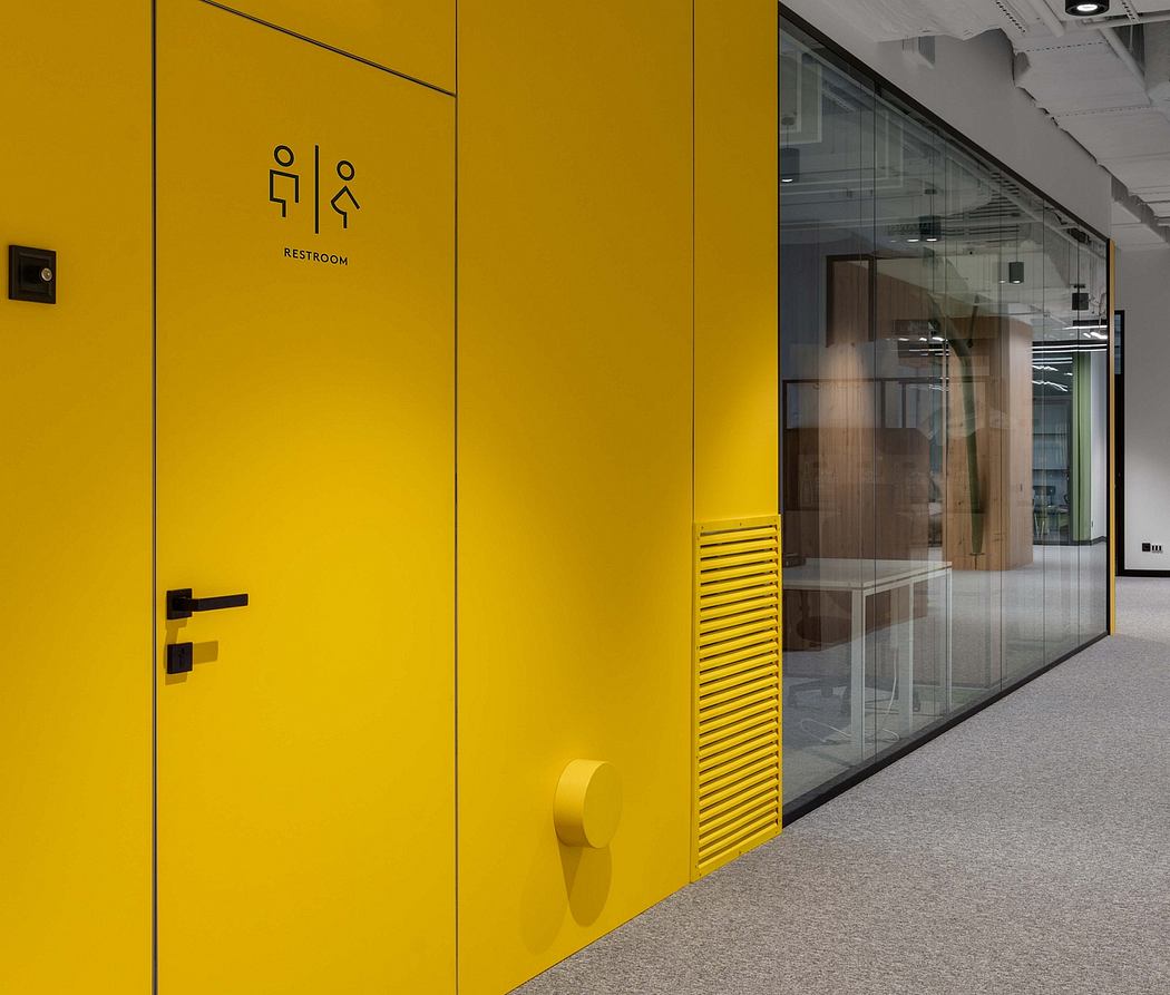 Striking yellow restroom doors with minimal signage, set against glass partitions.