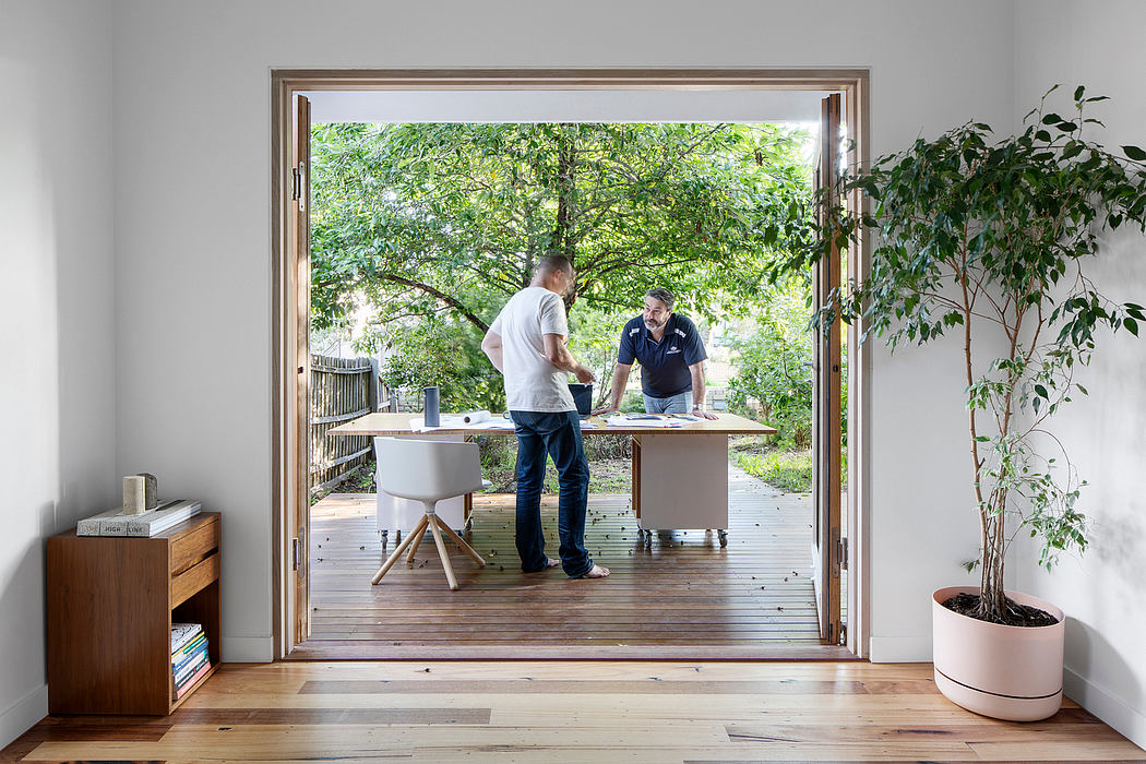 A modern, minimalist home office with large windows overlooking lush greenery.