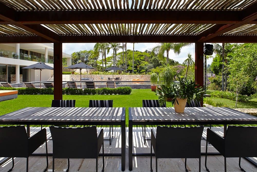 Elegant outdoor dining area with modern wooden furniture and lush tropical garden.