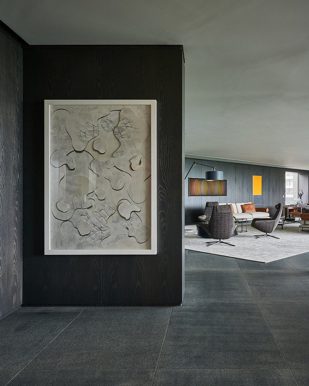 Modern interior design featuring a framed abstract wall sculpture, dark wood panels, and a cozy living space.