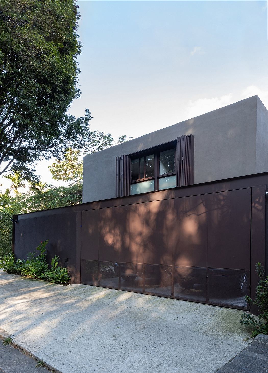 Modern minimalist architecture with sleek black facade, large windows, and lush green surroundings.