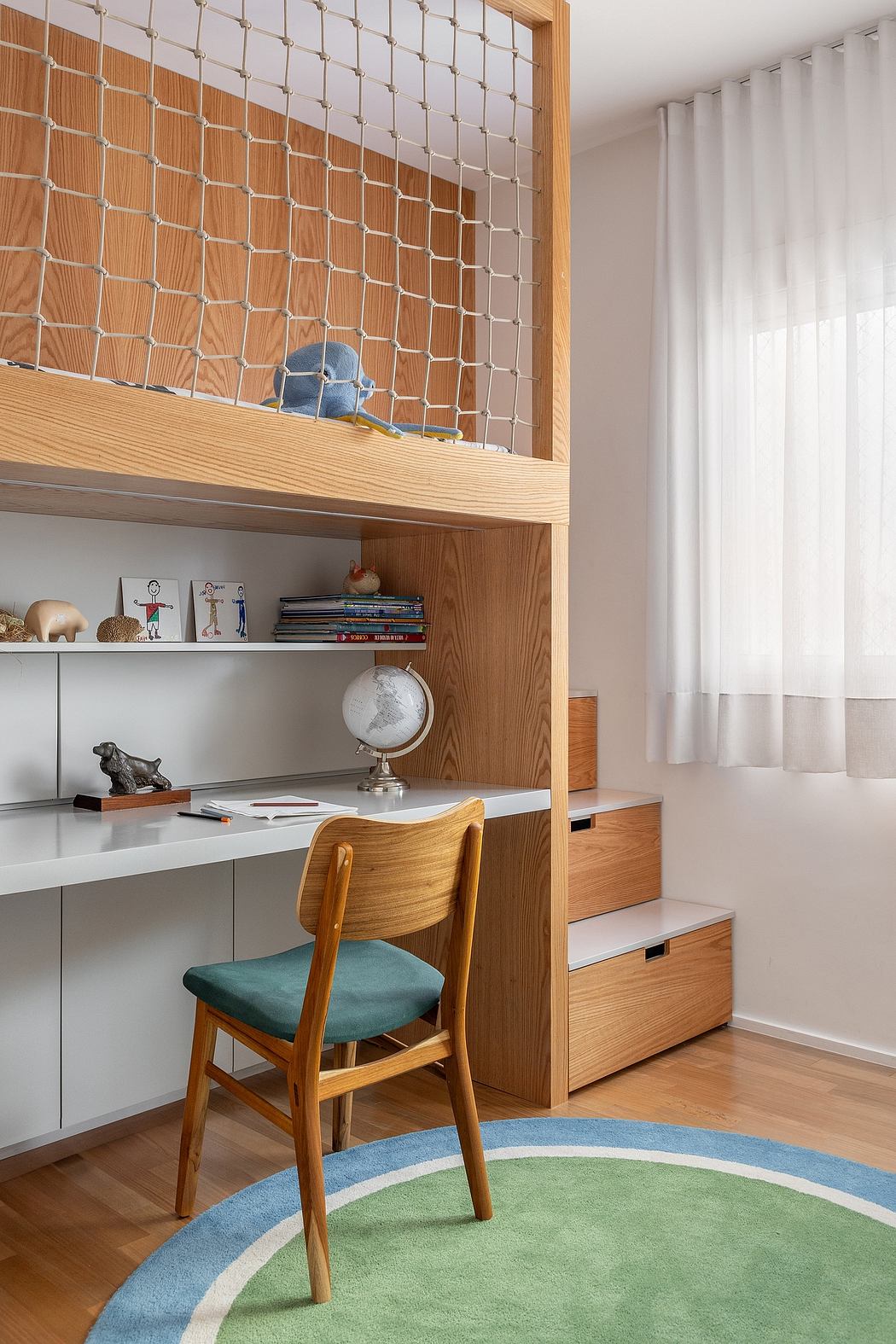 Cozy workspace with wooden shelves, desk, and green upholstered chair on a colorful round rug.