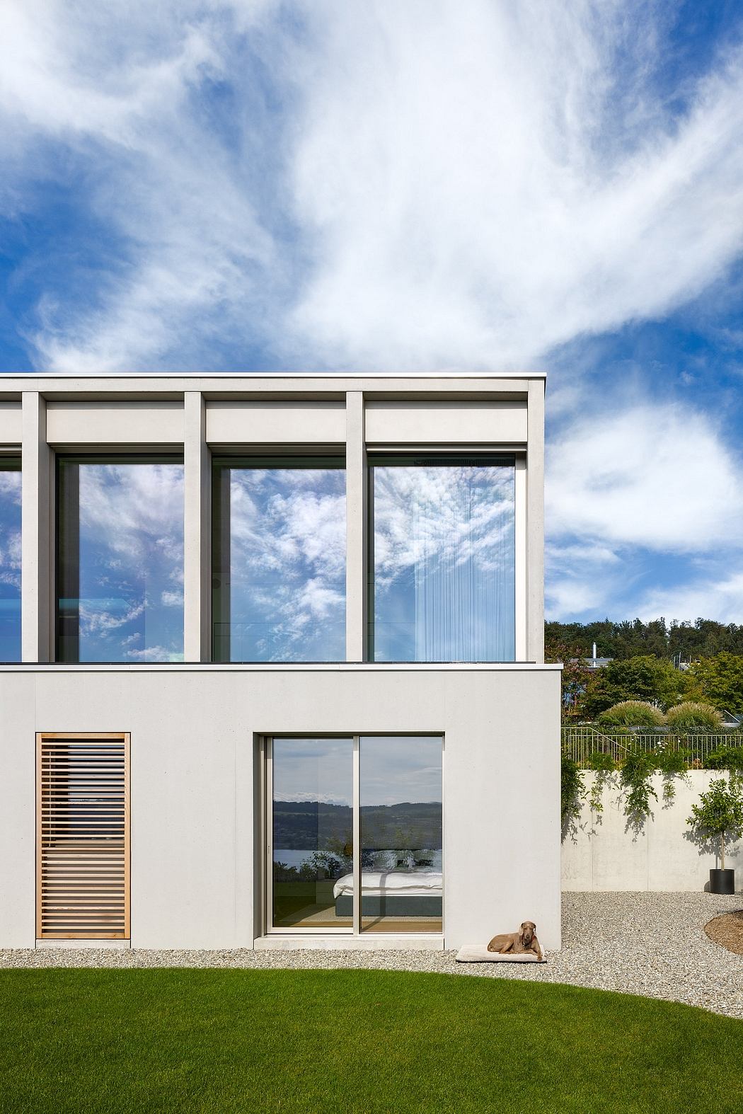 Contemporary home with clean lines, large windows, and a dog lounging on the lawn.