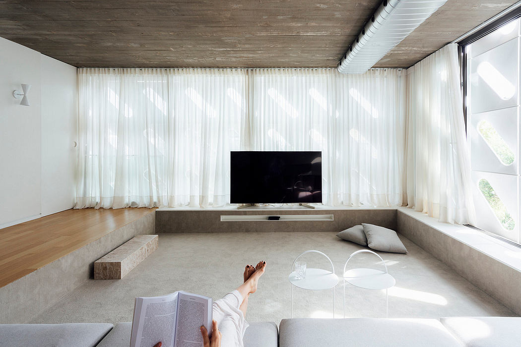 Minimalist living room with wooden ceiling, large windows, and sleek TV console.