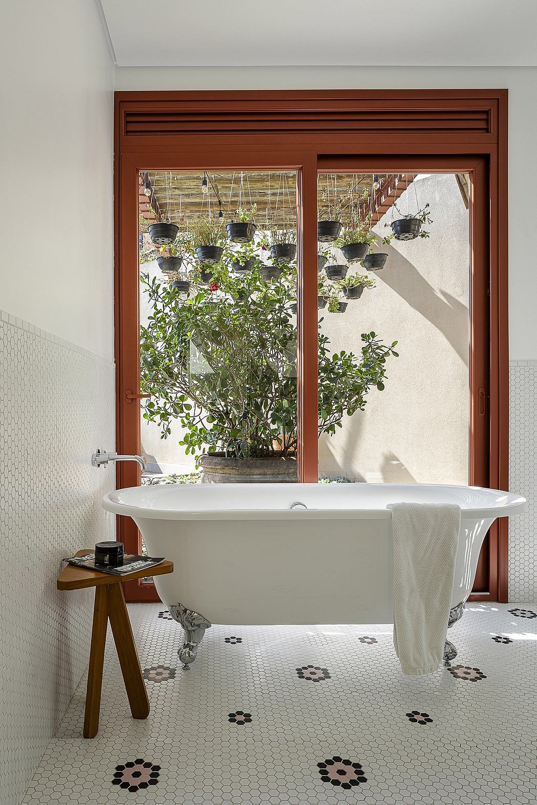 Cozy bathroom with potted plants, ornate wood frame, and floral-patterned tile floor.