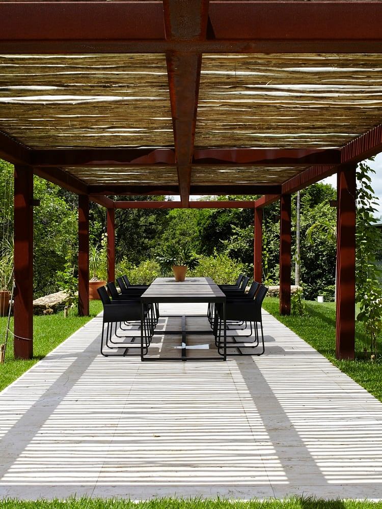 Wooden patio with a thatched roof, concrete platform, and modern outdoor furniture.