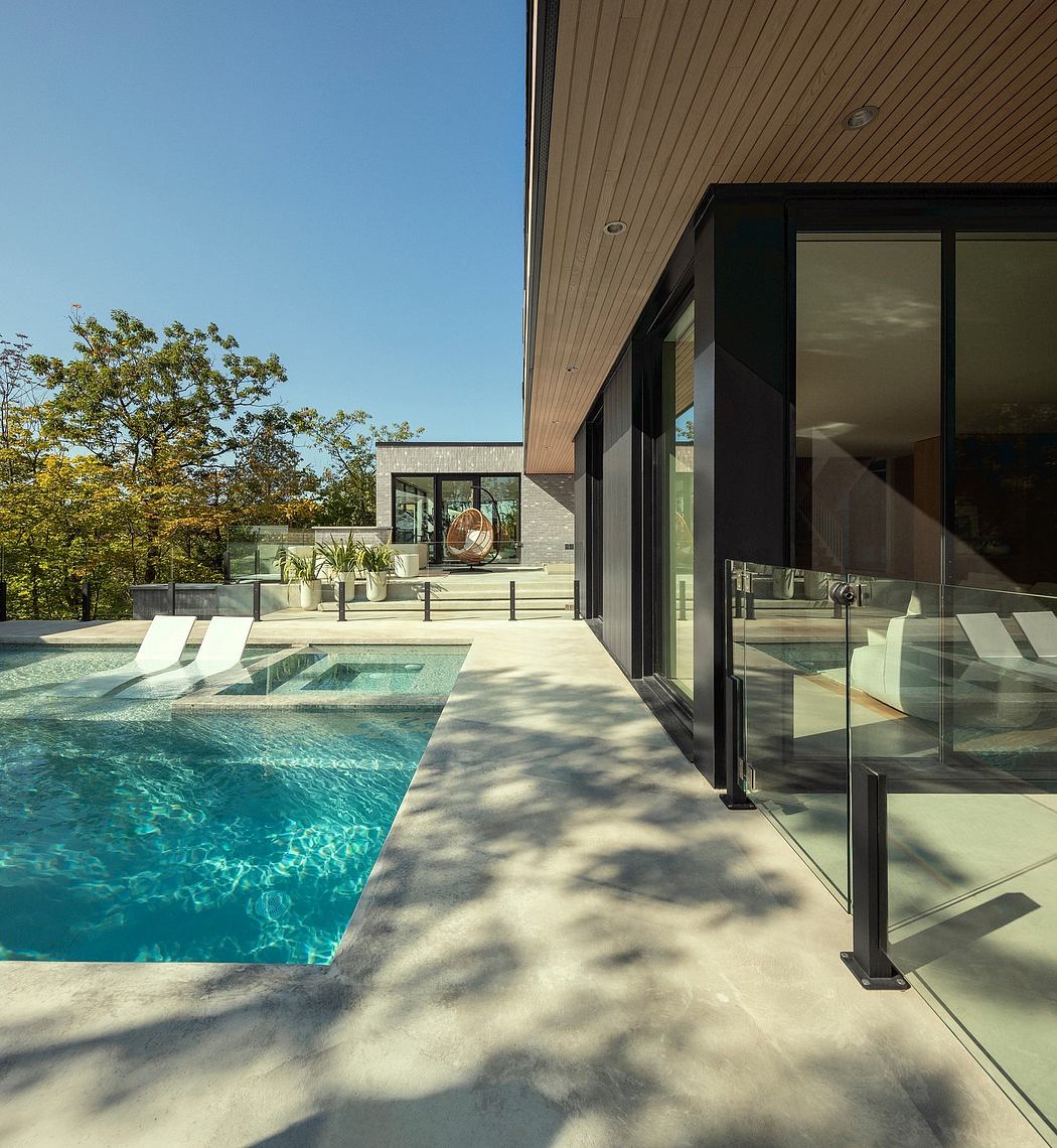 Sleek modern home with expansive glass walls, swimming pool, and landscaped patio.
