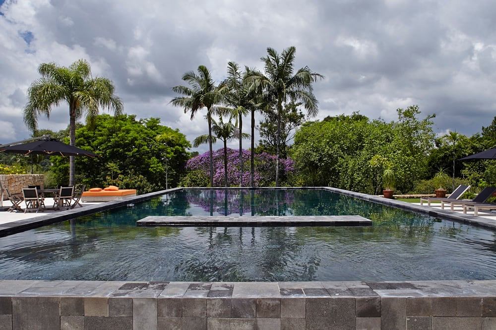 Lush tropical landscape surrounds a serene infinity pool with inviting lounge areas.