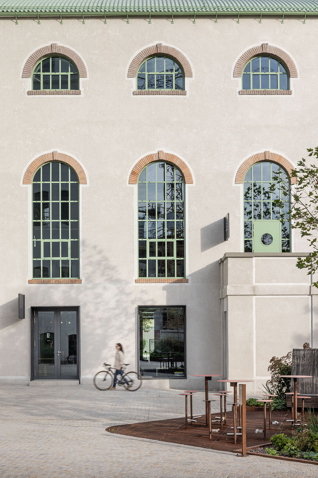 Large arched windows, brick detailing, and a modern seating area in this architectural facade.