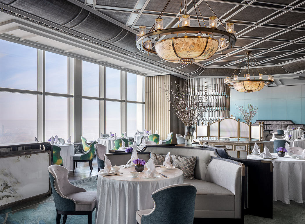 Elegant restaurant interior with ornate chandeliers, rich textures, and expansive windows.