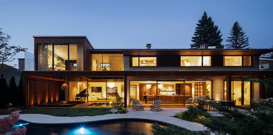 Sprawling two-story house with wooden exteriors, illuminated patio, and in-ground pool.