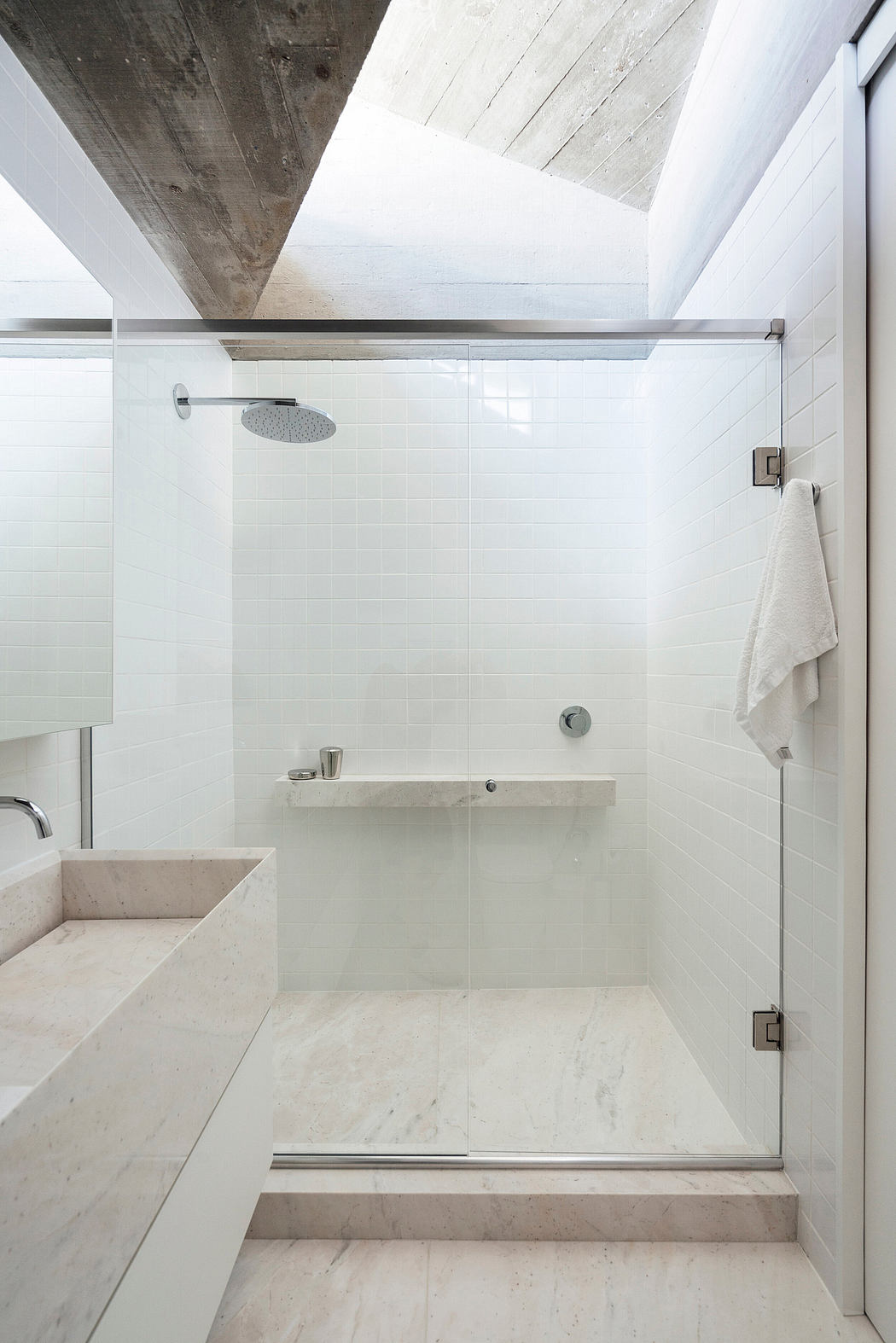 Minimalist bathroom with exposed concrete ceiling, white tiles, and a modern shower.