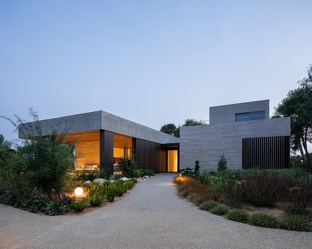 Contemporary concrete and wood home exterior with illuminated entryway and landscaped garden.
