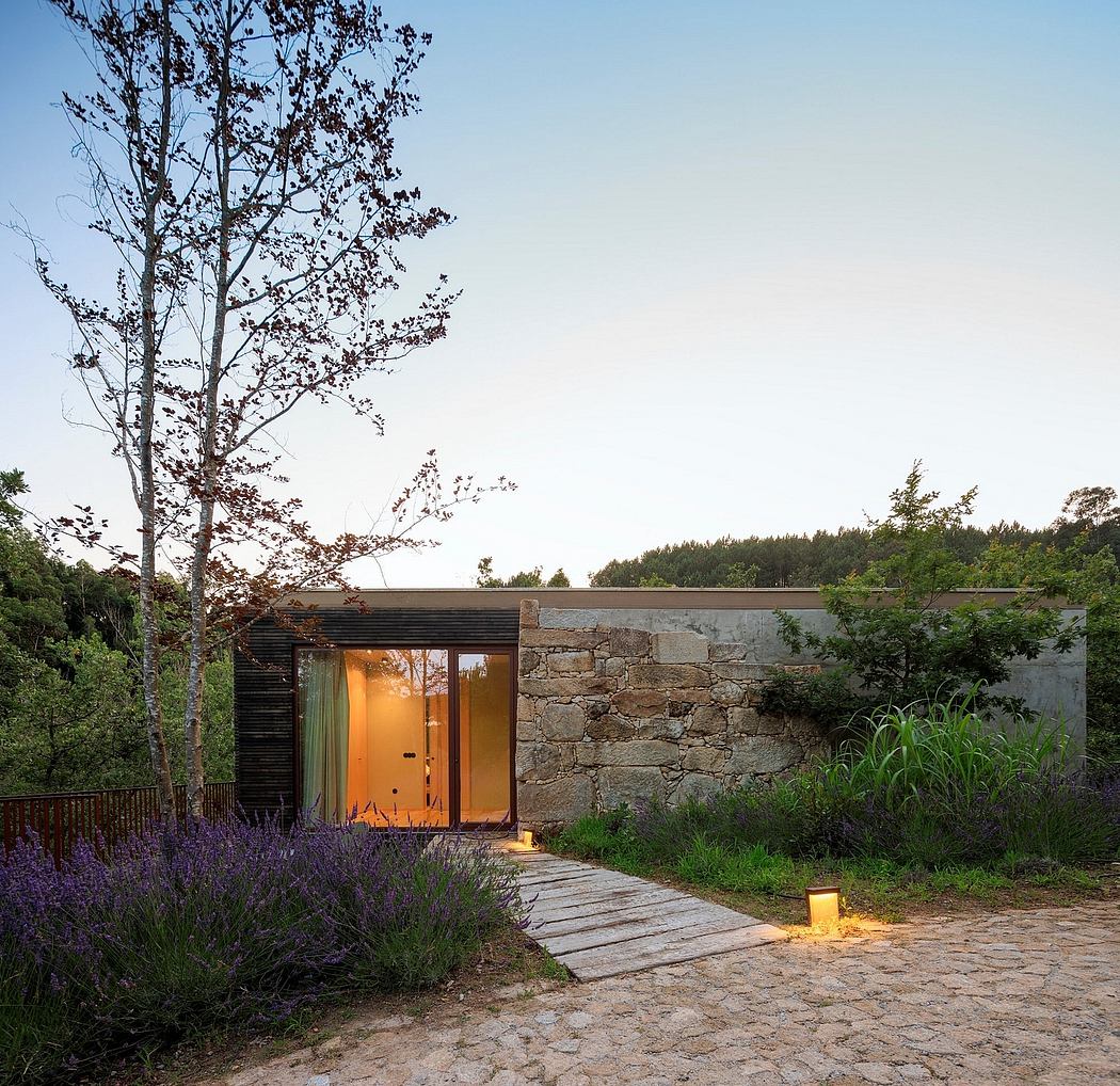 A rustic wooden structure with stone walls and a softly illuminated entrance surrounded by lush greenery.
