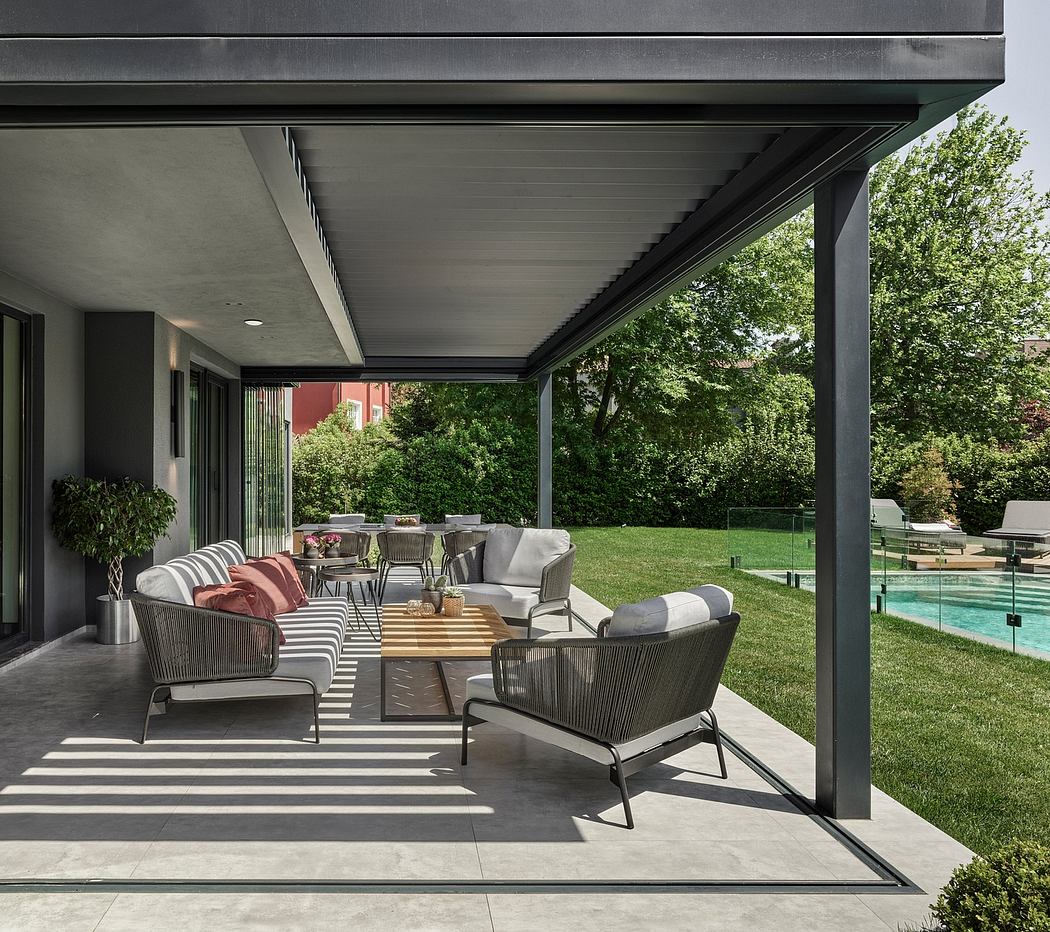 An outdoor living space with a covered patio, comfortable seating, and an inground pool.
