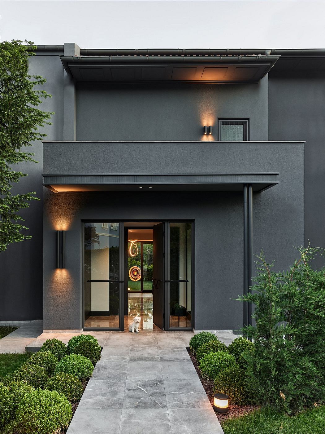 A sleek, modern exterior with a bold black facade, large glass windows, and carefully landscaped greenery.