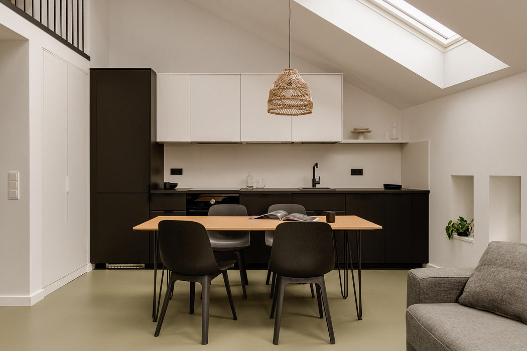 A bright, modern kitchen with sleek black cabinets, wooden dining table, and pendant lighting.