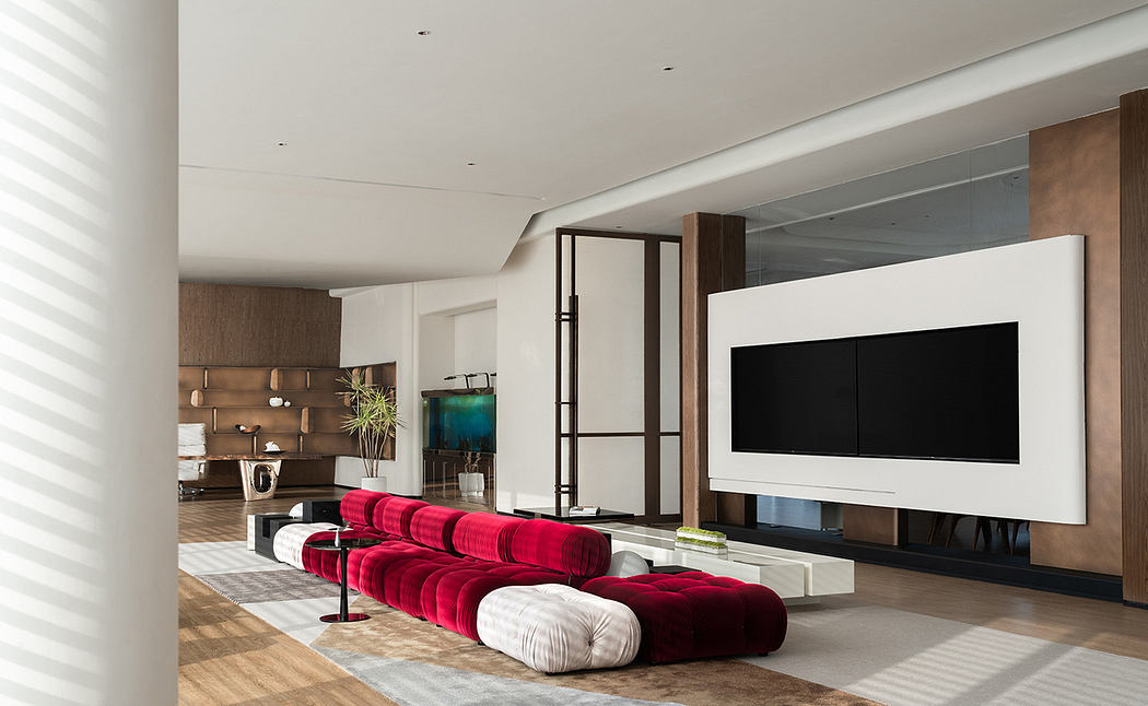 A sleek and modern living room with large white TV, plush red sofa, and minimalist decor.