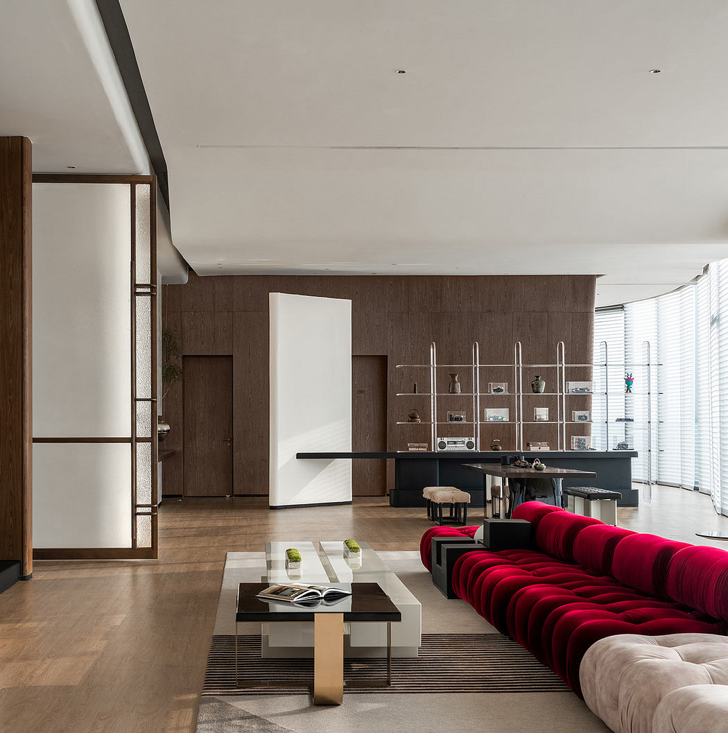 Striking modern living room with red tufted sofa, shelving, and large windows.