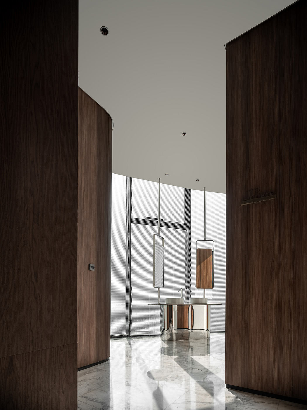 A minimalist hallway with modern light fixtures, wooden panels, and marble floors.