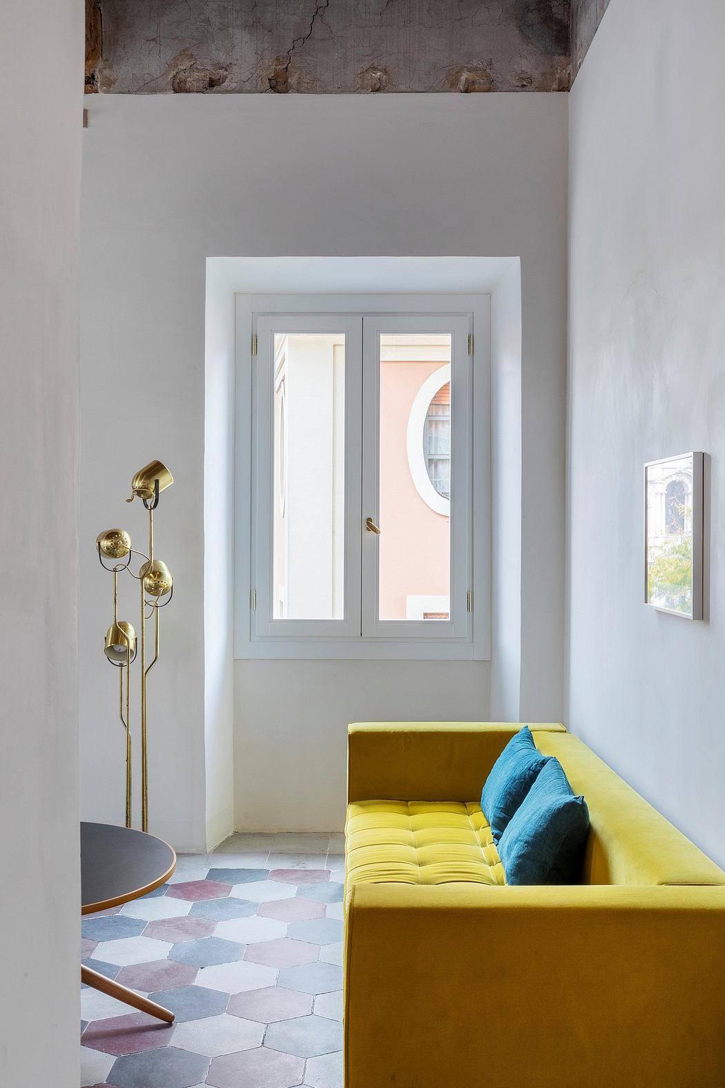 A modern interior with a yellow sofa, hexagonal floor tiles, and a window with arched trim.
