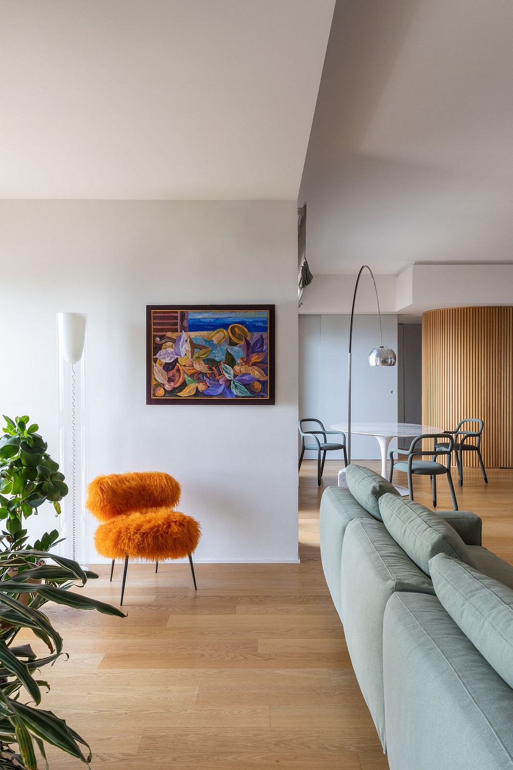 Bright, modern living space with abstract artwork, plush orange chairs, and wooden floors.