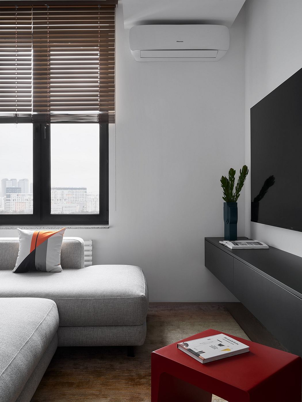 A modern living room with sleek gray furniture, wooden blinds, and a minimalist design.
