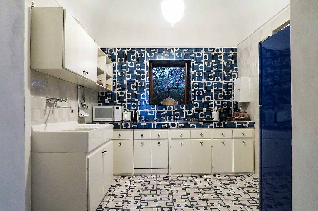 A modern, bold kitchen with abstract patterned tiles, white cabinets, and a window.