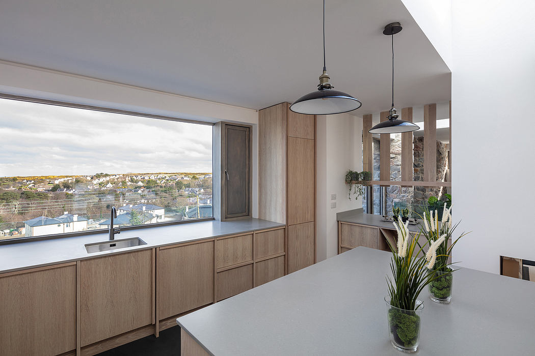 A modern, open-concept kitchen with sleek wood cabinetry, pendant lights, and expansive city views.