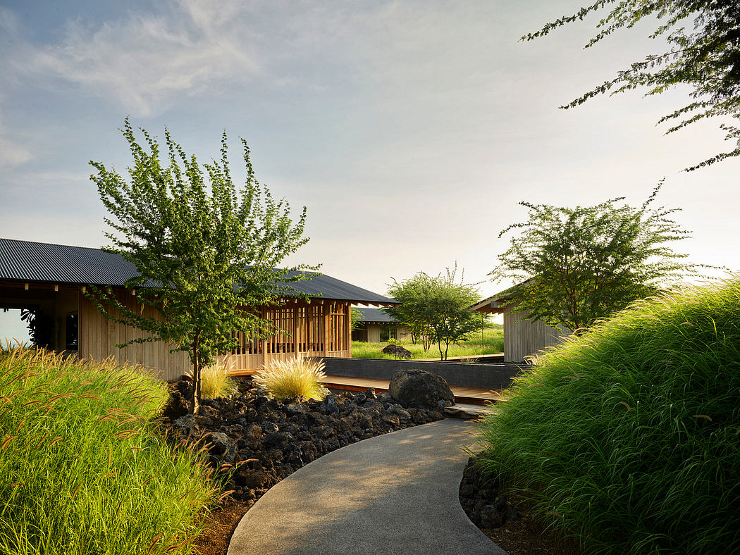 Serene Japanese-inspired garden pathway leading to modern wooden structures with lush greenery.