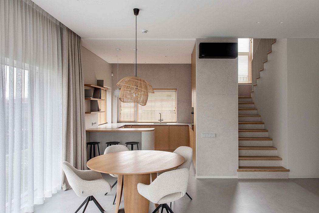 Minimalist, open-concept living space with natural wood furnishings, neutral tones, and a statement pendant lamp.