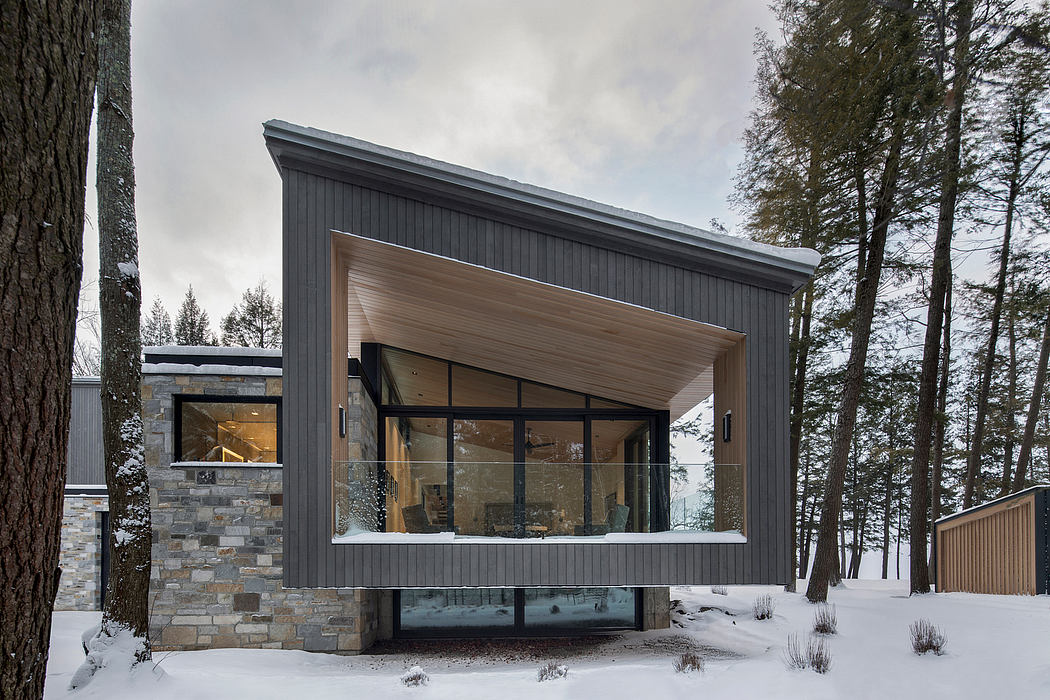 A striking modern cabin with large windows, stone accents, and a cantilevered design.